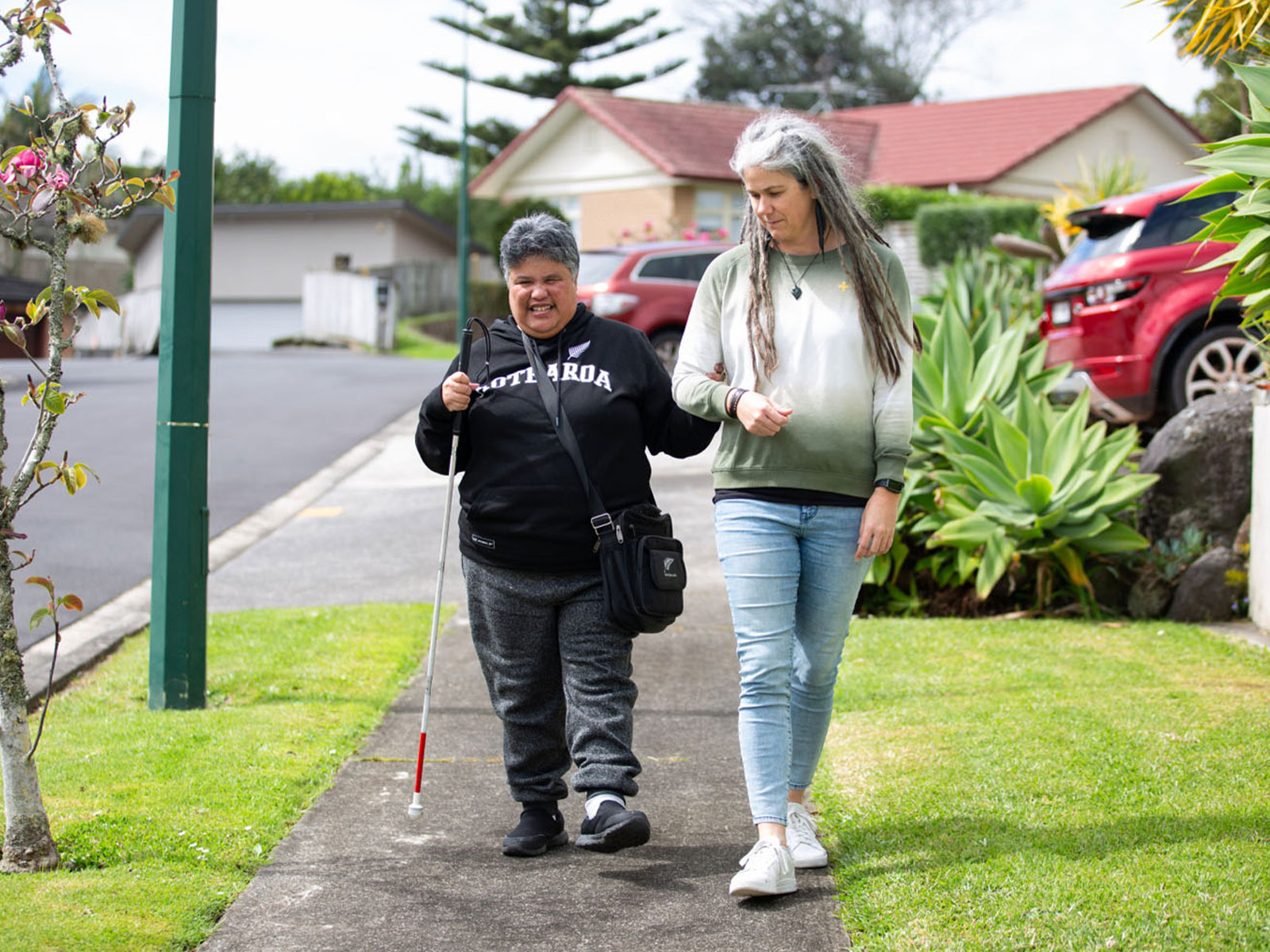 two women walking side by side on a suburban path