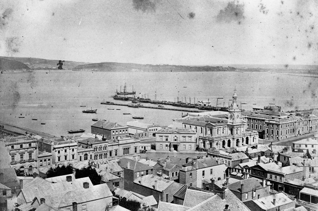 Overlooking Dunedin city buildings, harbour, and wharves, c1870s