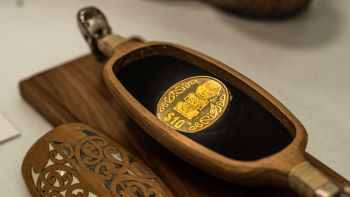 Gold Pūkaki coin in waka huia (treasure box)